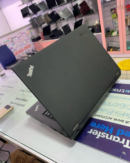 Lenovo Thinkpad T440P business laptop with black keyboard and screen, placed on a wooden desk.